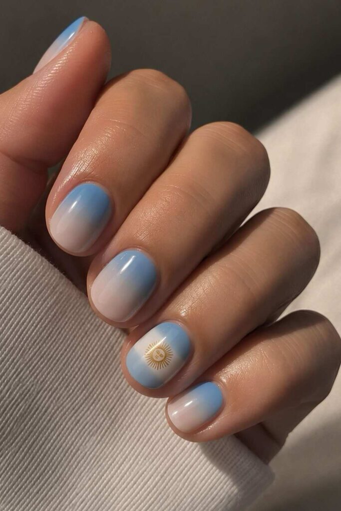 Argentina ombré nails with soft blue, white, and flag accent