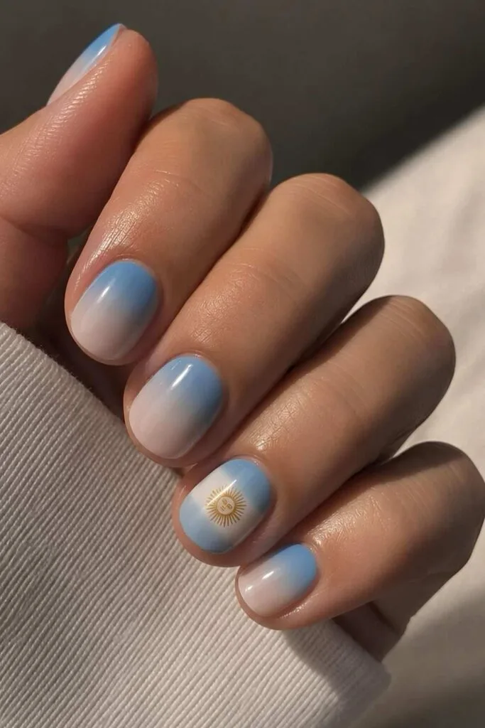 Argentina ombré nails with soft blue, white, and flag accent