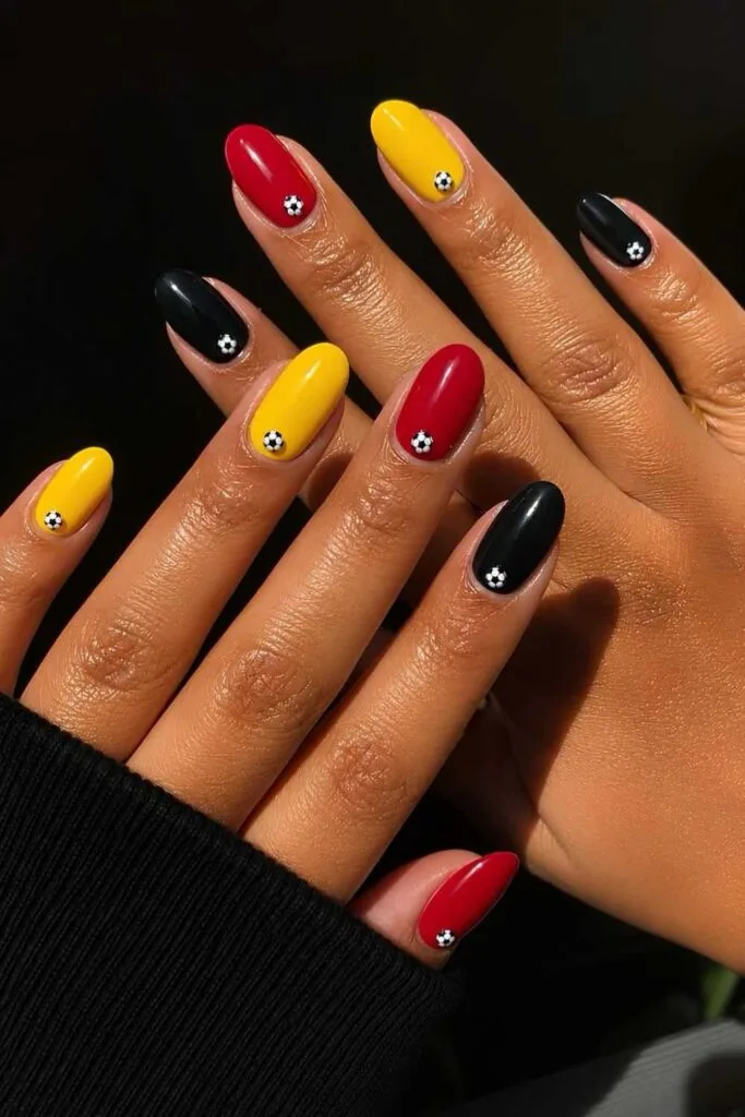 Belgium skittle nails in black, yellow, and red with football accents