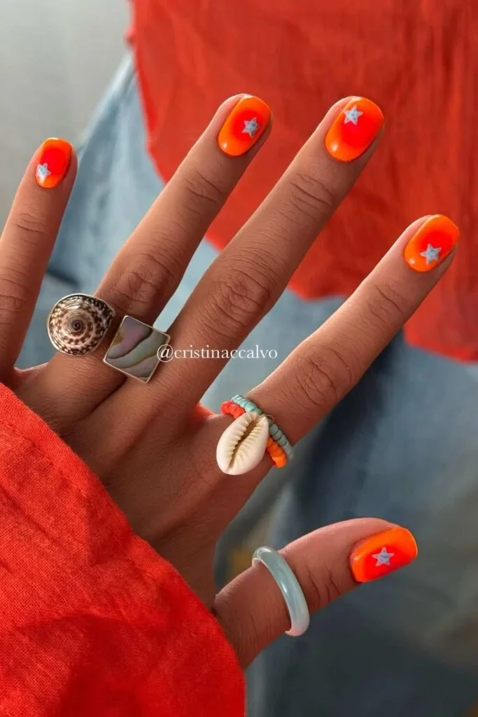Neon orange nails with aura effect and silver stars