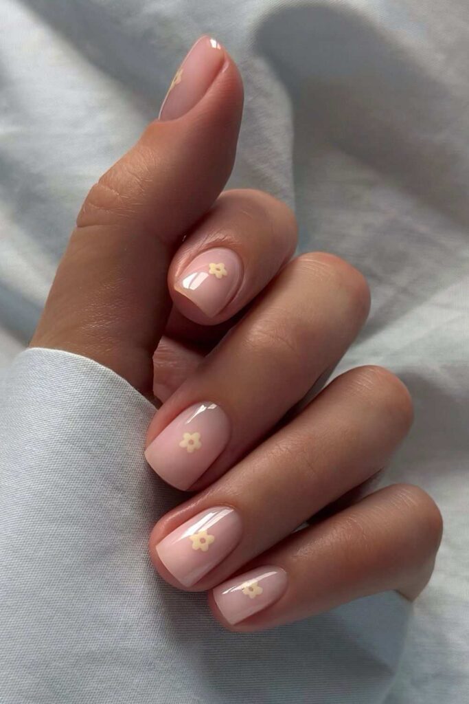 Glossy neutral nails with tiny pale yellow florals