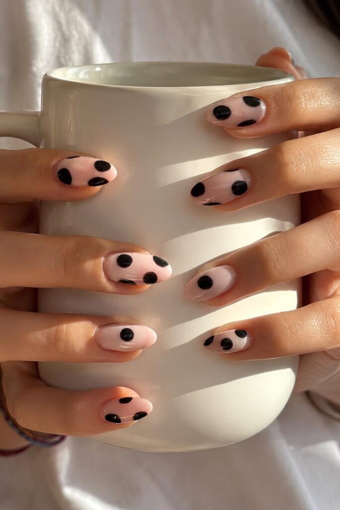 Milky white nails with oversized black polka dots