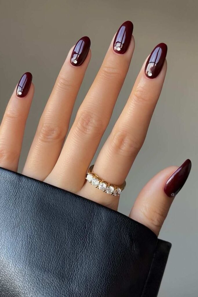 Maroon almond nails with diamond accents