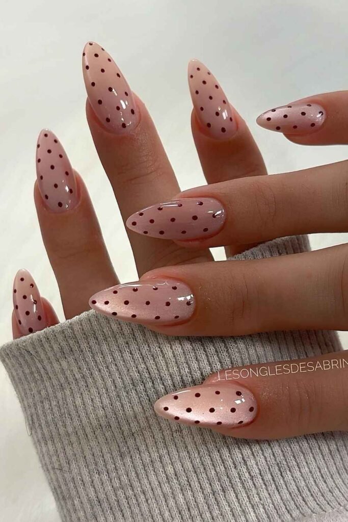 Pink cat-eye almond nails with dark polka dots