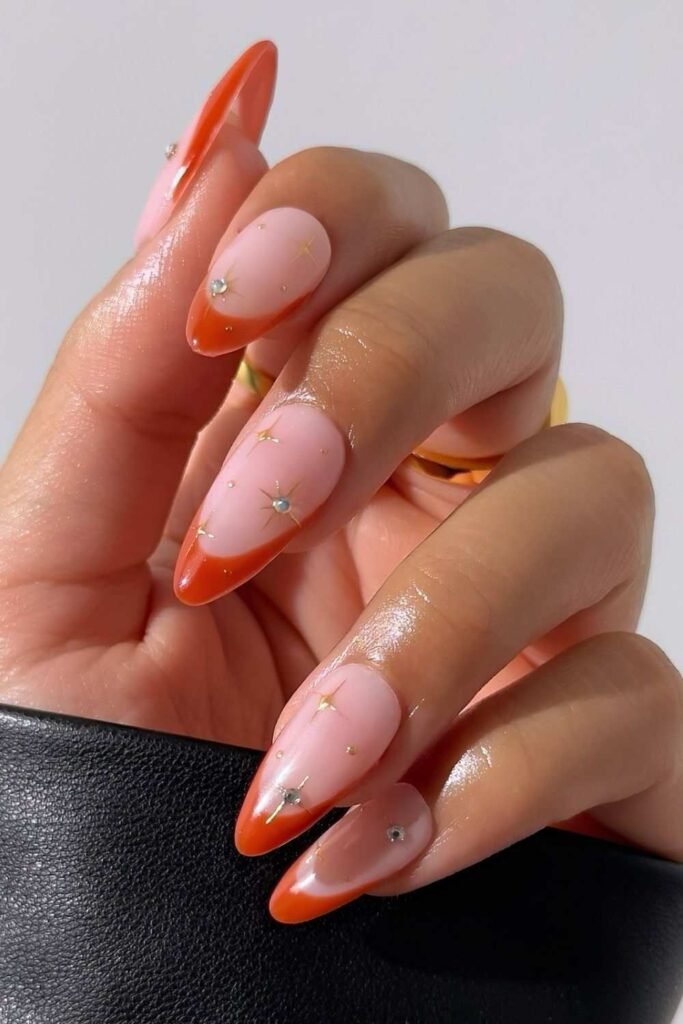 Pumpkin orange French nails with tiny gold stars
