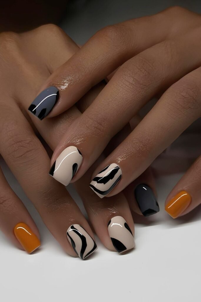 Short mismatched nails with zebra print and orange nail accent